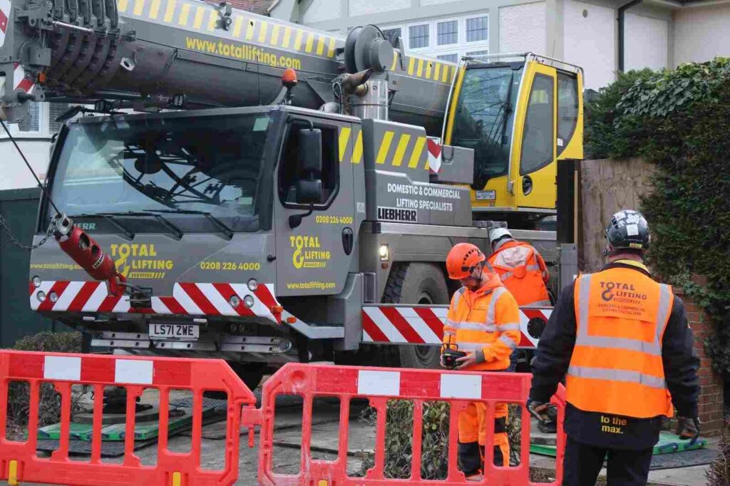 Workers and a Total Lifting Services crane working on site